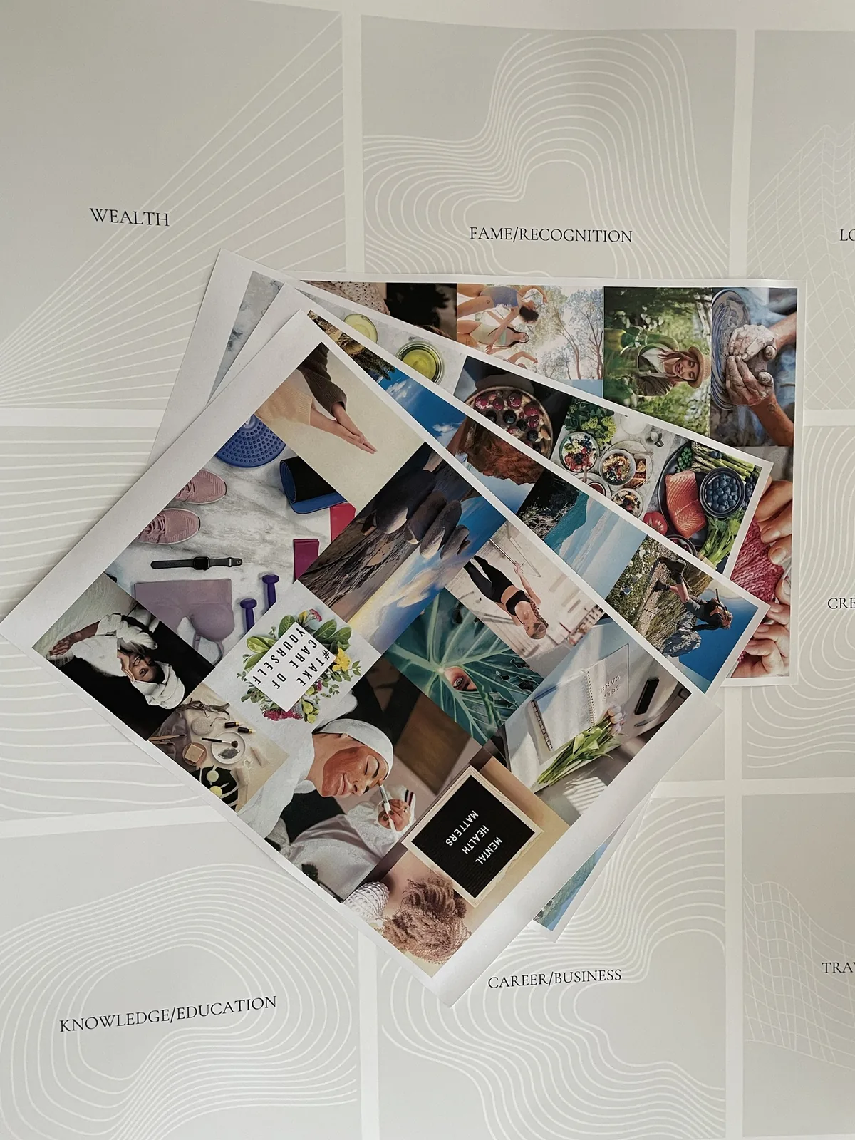 Printed photo sheets fanned out on my vision board poster, before I cut and glue anything