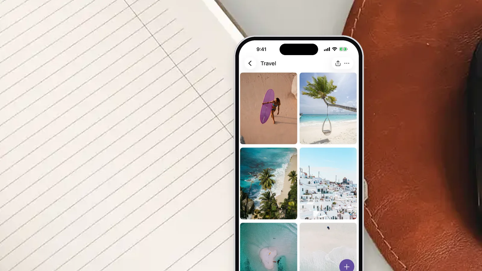 An iPhone on an open notebook showing the Travel area of a vision board in the VISIYA app, filled with beach and island photos
