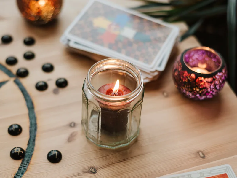 Cards, glass beads and burning tea lights on a wooden table