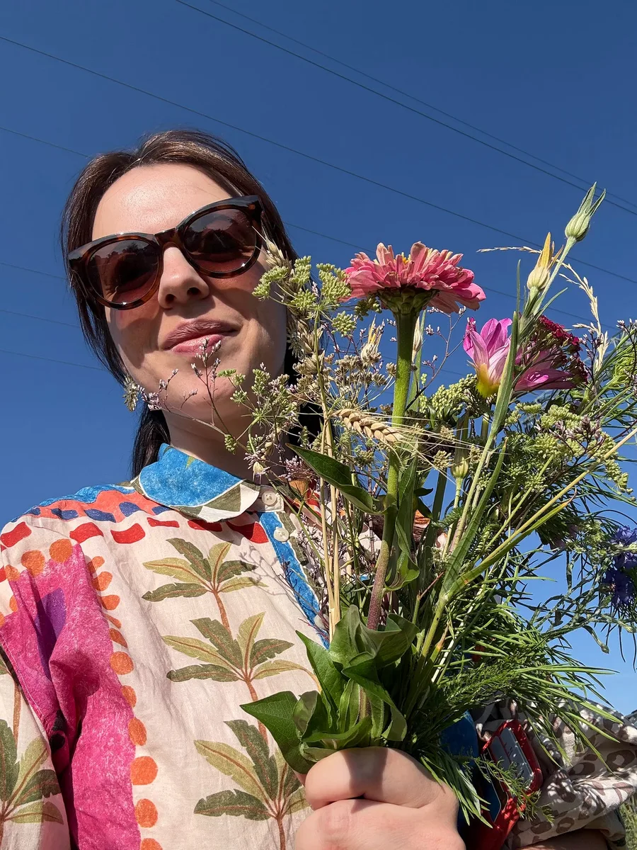 Marina holding a bunch of flowers she picked herself against a blue sky