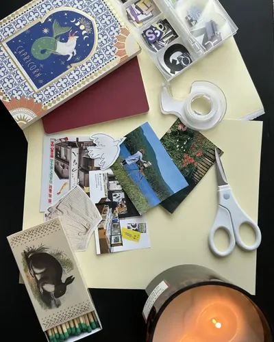Magazine cut-outs, tape, scissors and a lit candle on pale paper