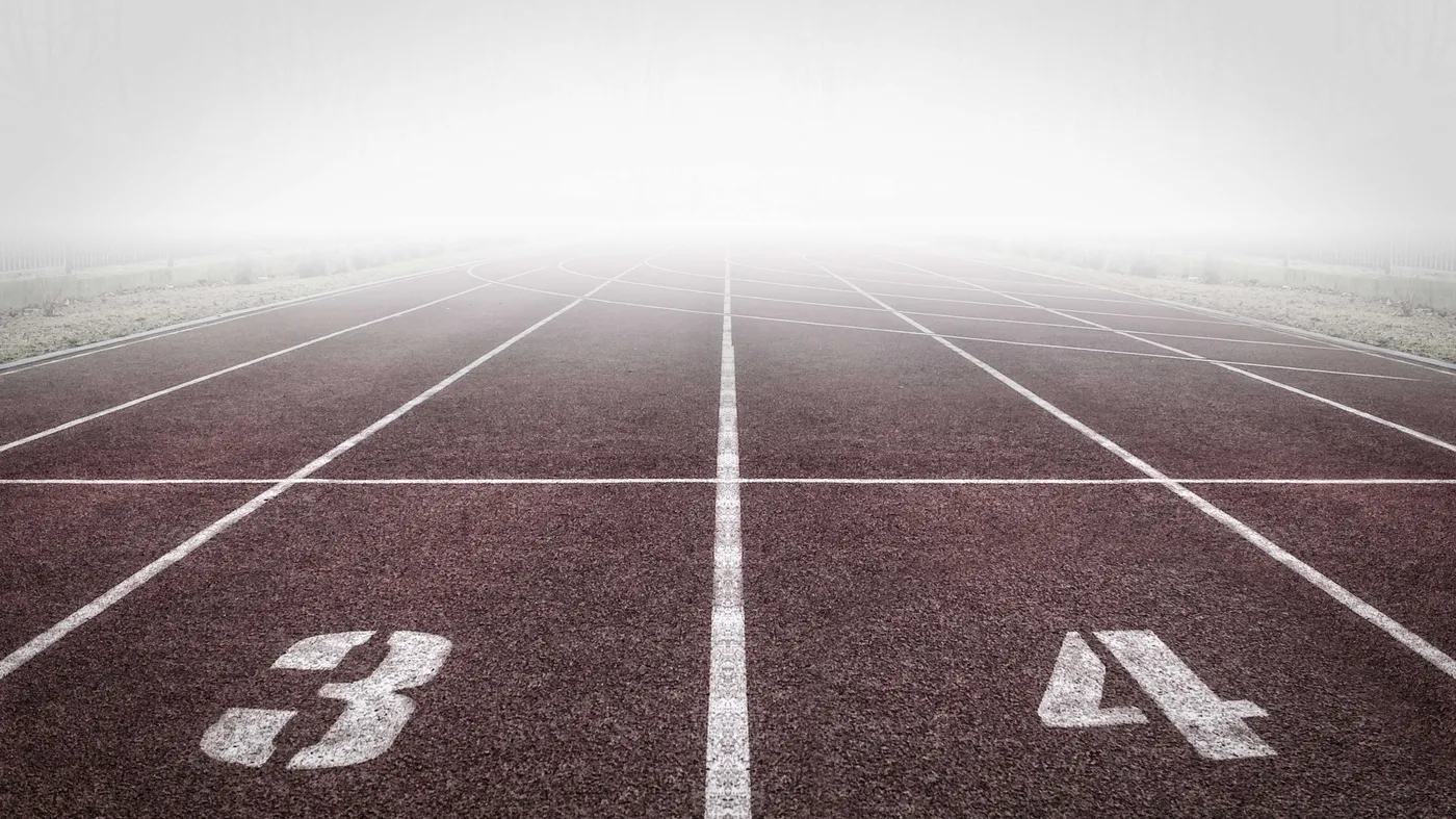 Foggy running track with lanes numbered 3 and 4 stretching into the mist