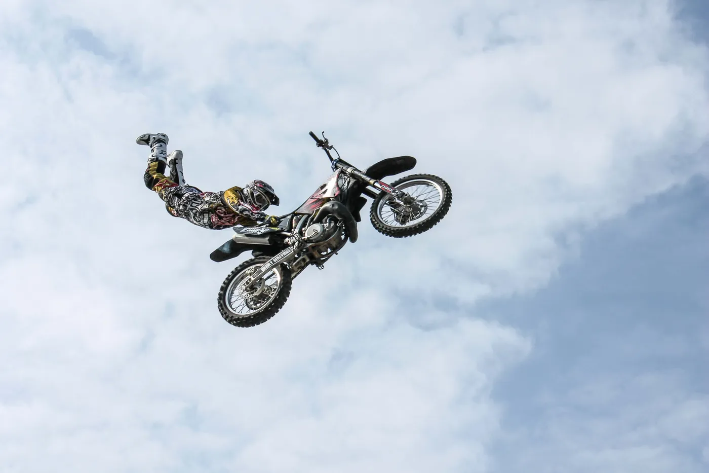 A freestyle motocross rider soaring through a cloudy sky mid-stunt, symbolising the brightness of life