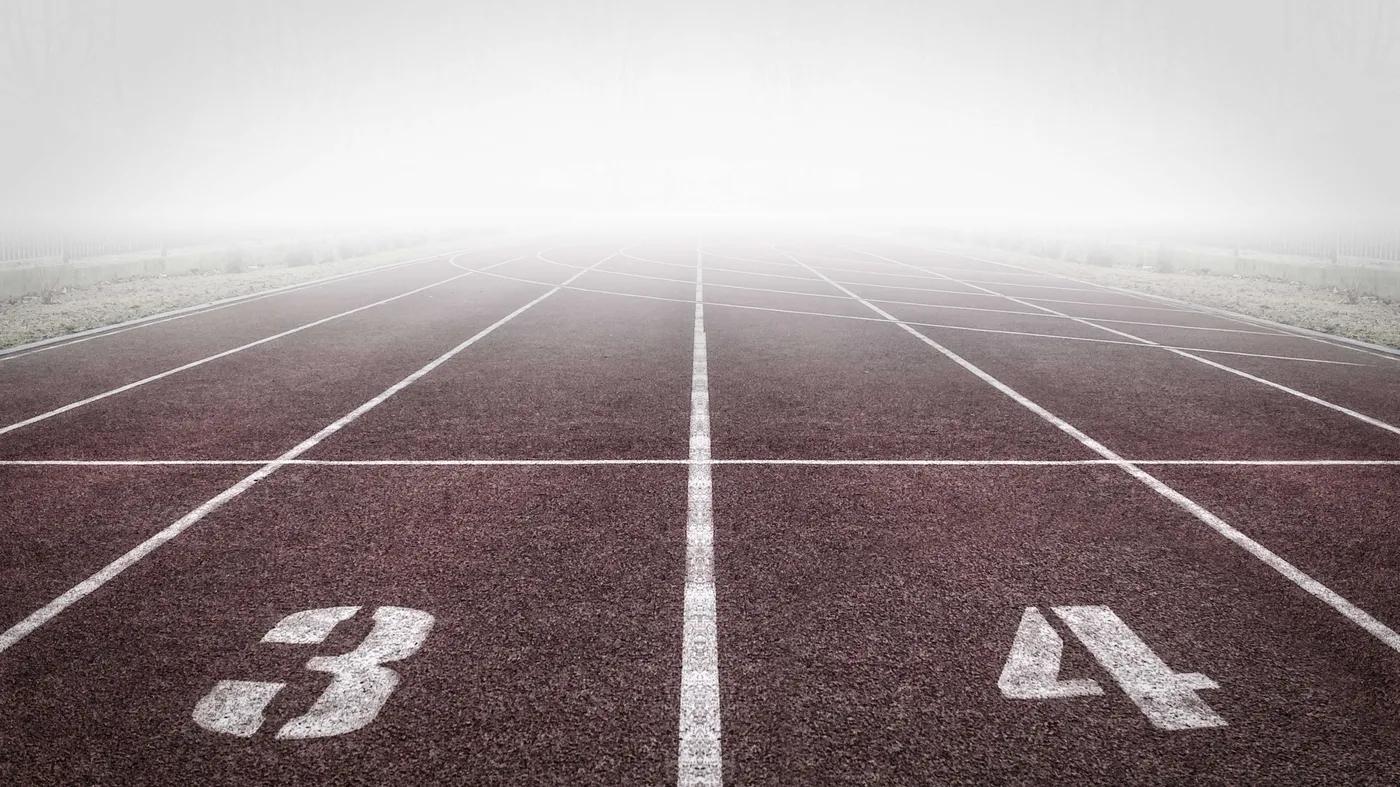 Foggy running track with lanes numbered 3 and 4 stretching into the mist