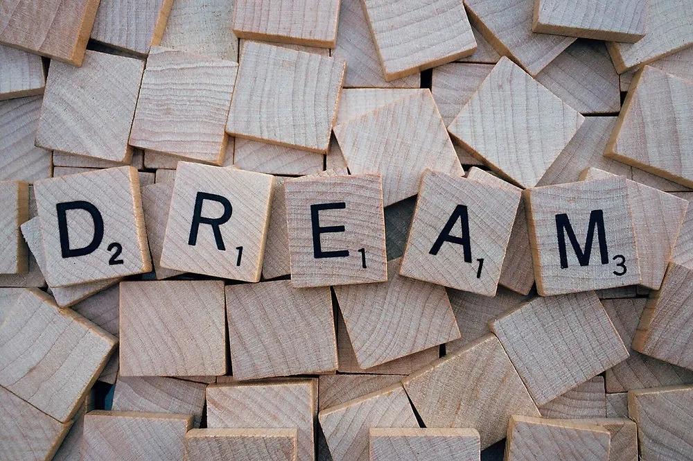 Дерев’яні плитки з літерами, складені у слово DREAM, серед розсипу фішок