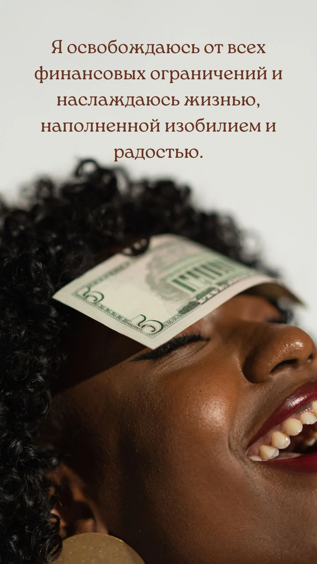 Карточка денежной аффирмации: улыбающаяся женщина с купюрой на лице с надписью «Я освобождаюсь от всех финансовых ограничений и наслаждаюсь жизнью, наполненной изобилием и радостью.»