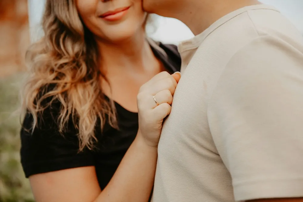 A close-up of a couple embracing, the woman wearing a delicate ring
