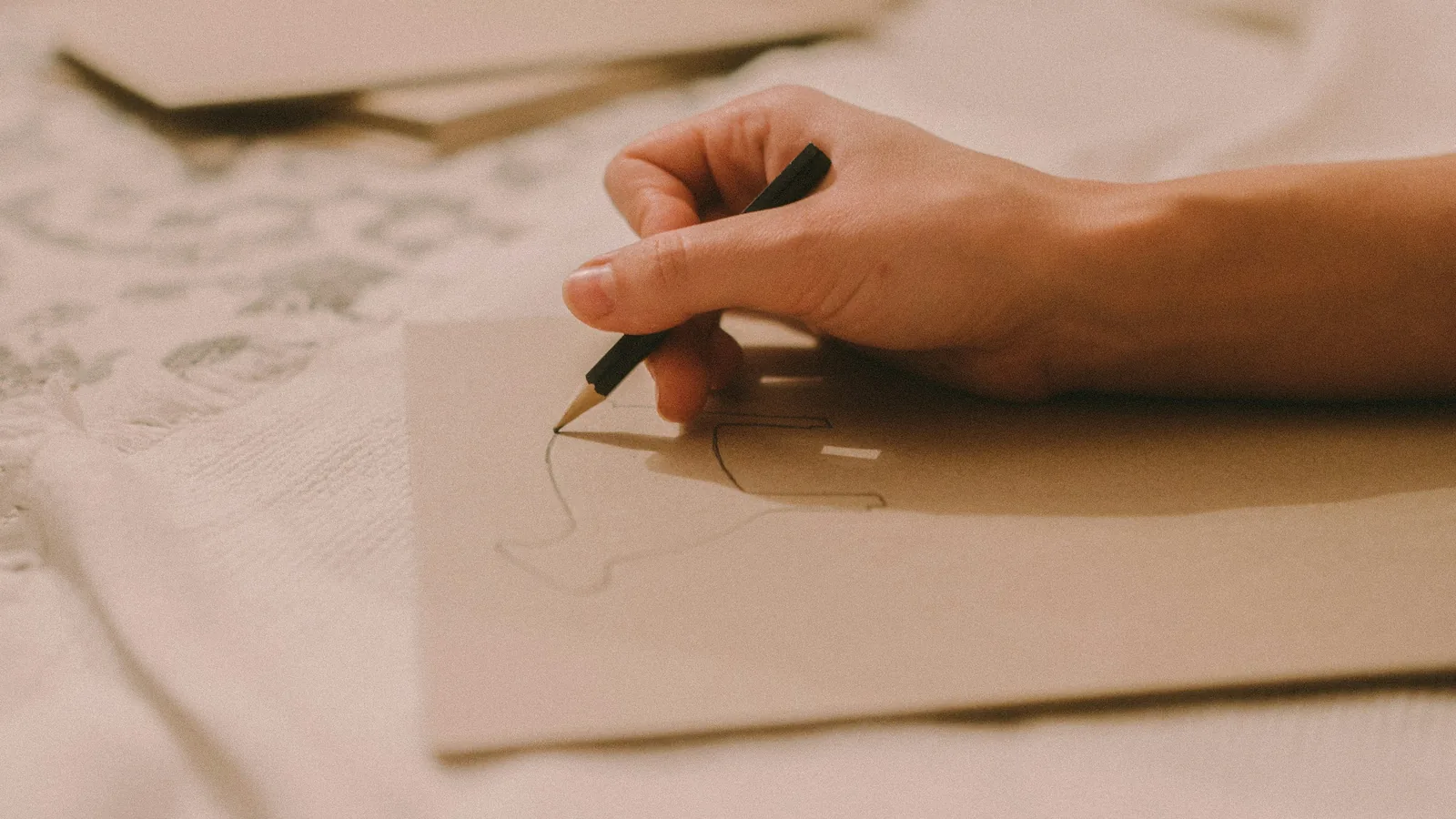 Eine Hand mit Bleistift auf einer kleinen Karte, dahinter weitere Karten