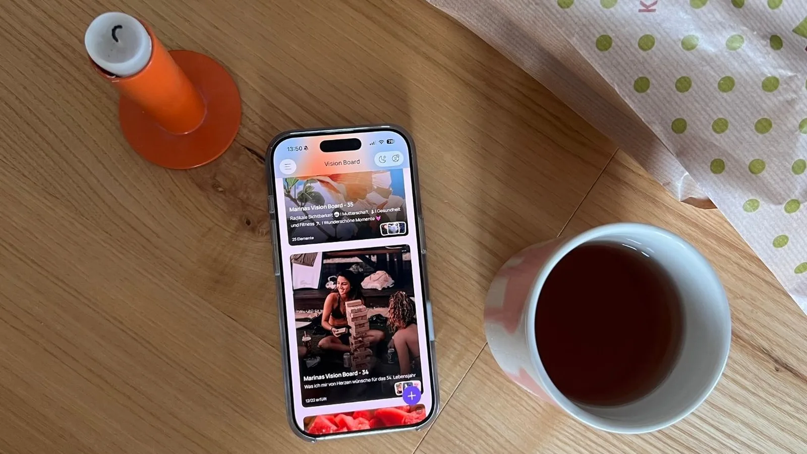 Marinas iPhone mit ihren beiden Jahres-Boards in VISIYA: „Marinas Vision Board – 35“ mit dem Motto „Radikale Sichtbarkeit“ in der Unterzeile und „Marinas Vision Board – 34“ mit „12/22 erfüllt“, daneben eine Kerze und eine Tasse Tee